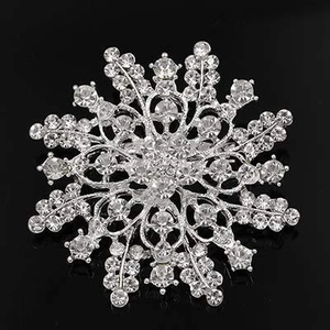 Detailed view of a silver snowflake brooch with sparkling crystal rhinestones on black