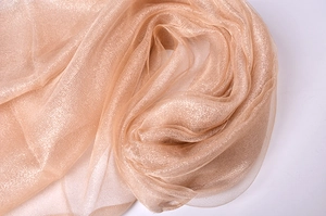 Detailed close-up of champagne silk organza fabric with shimmering metallic gold threads