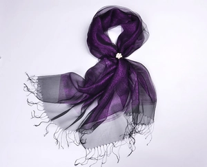 Detail of purple silk organza scarf with shimmering tassels and white flower brooch