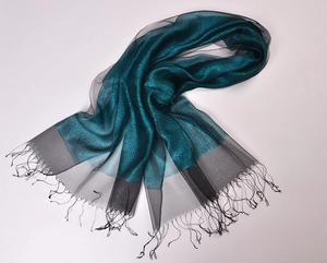 Detail of silk organza scarf showing dark teal gold silk texture and black mesh tassels