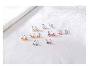 Macro shot of natural freshwater pearl earrings in various colors and sizes on white fabric