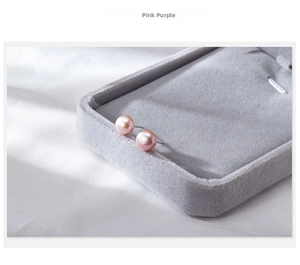 Macro shot of pink-purple freshwater pearl earrings on a soft grey velvet tray