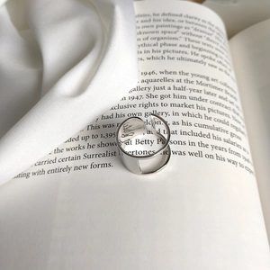Minimalist silver open ring placed on vintage book with white silk fabric detail