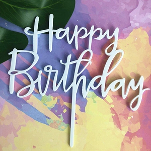 Close-up of white acrylic Happy Birthday cake topper over a vibrant colorful background