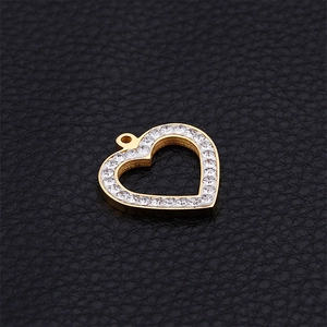 Golden hollow heart pendant with white rhinestones on black textured background