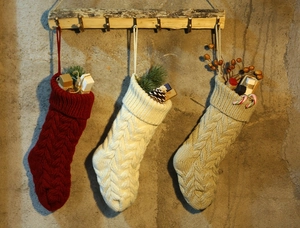 Detailed cable knit Christmas stockings in red, white and beige with festive gifts