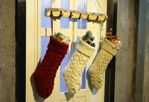 Detailed view of rustic knitted Christmas stockings with pine cones and classic cables