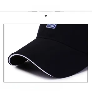 Detail of sturdy curved brim with white sandwich piping on a black cotton baseball cap