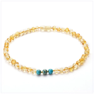Détail d'un collier en ambre de la Baltique avec touches de turquoise sur fond blanc
