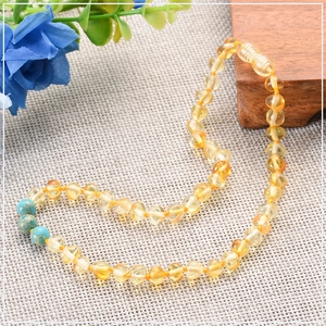 Détail macro du collier en ambre pour bébé avec perles de turquoise et améthyste