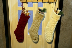 Close-up of knit Christmas stockings in red, khaki and white hanging with holiday gifts