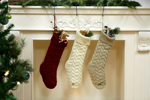 Close-up of three knitted Christmas stockings in red, beige and khaki on a fireplace