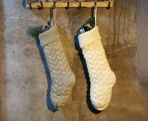 Detail view of large knit Christmas stockings in beige and cream with cable texture