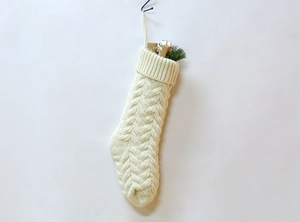 Close-up of white knitted Christmas stocking with vintage cable stitch texture detail