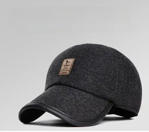 Detailed close-up of dark grey wool baseball cap with brown leather logo and leather brim edging