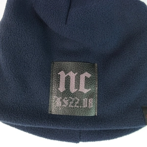 Detail of navy fleece beanie with black leather patch featuring gothic lettering