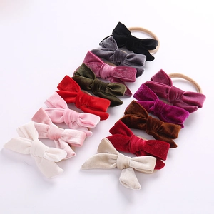 Detailed view of 12 colorful velvet bow nylon headbands for babies on white backdrop