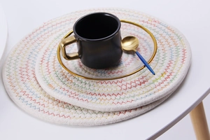 Macro shot of a round woven coaster set with colorful stitching and a stylish coffee cup