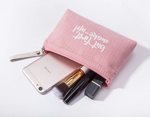 Pink striped canvas makeup bag with zipper showing internal storage capacity and white wristlet