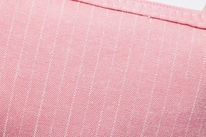 Macro close-up showing pink striped canvas fabric texture and precise stitching on the makeup bag