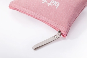 Detail of pink striped canvas pouch featuring a smooth zipper and grey fabric puller