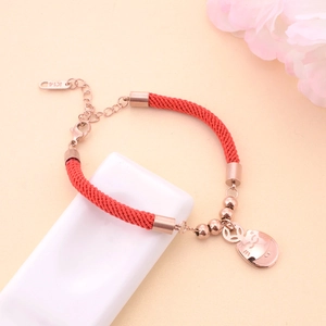 Detail of rose gold lucky cat charm on a red braided bracelet with K14 gold engraving