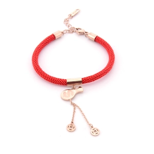 Macro detail of rose gold dollar money bag and coin charms on red string bracelet