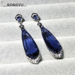 Detail of blue teardrop crystal earrings with silver setting and zircon accents
