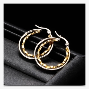 Detailed macro view of two-tone twisted hoop earrings with 925 silver hallmark logo