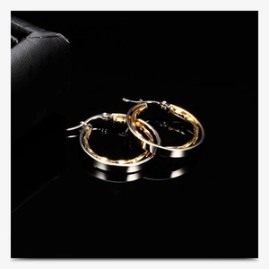 Macro shot of two-tone gold and silver 28mm hollow round earrings on reflective black