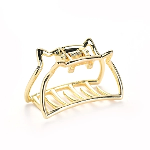Detail view of a hollowed golden metal cat-shaped hair claw clip with a glossy finish