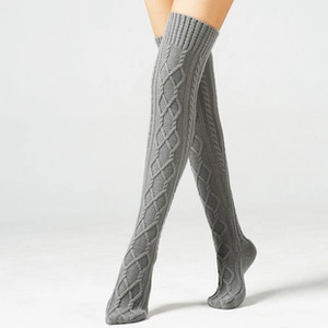 Close-up of gray chunky cable knit over-knee socks featuring thick thermal wool texture