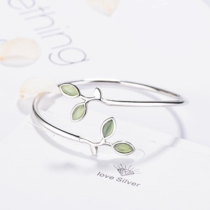 Minimalist silver-colored open bangle featuring green leaf-shaped cat-eye stones