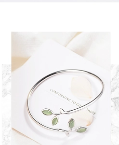 Detail of silver sprout bracelet with cat eye stone leaves on a floral background
