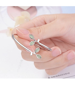 Detail of silver leaf bracelet with green cat-eye stones shown worn on a hand