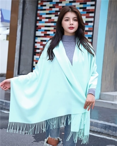 Close-up of light mint green cashmere-like scarf with fringe details worn by a model
