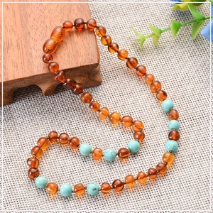 Detailed shot of amber and turquoise teething necklace on woven texture background