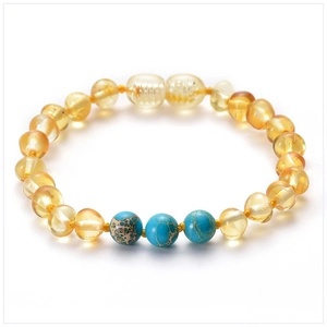 Macro detail of Baltic amber baby bracelet with turquoise beads on white background