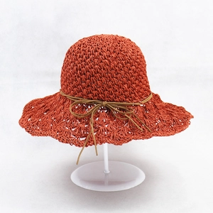 Handmade crochet straw sun hat in bright brick red with a wavy brim and bow accent