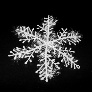 Detailed macro shot of a white fuzzy Christmas snowflake decoration on black background