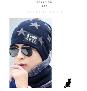Close-up of navy blue knitted beanie and scarf set with grey star patterns and leather label