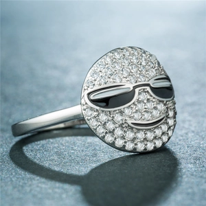 Gros plan d'une bague smiley argentée ornée de zircons blancs et de détails en émail