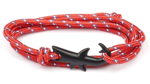 Close-up of a red nautical braided rope bracelet with a matte black shark-shaped clasp