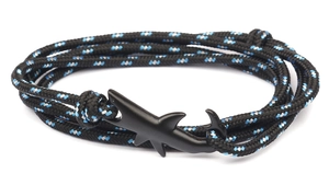 Detailed close-up of a black matte shark-shaped anchor clasp on a braided nylon rope bracelet