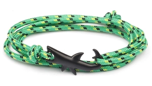 Detail of green and yellow paracord bracelet with a matte black shark shaped clasp