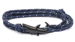 Detail of shark-shaped matte black hook and blue woven rope on a nautical bracelet