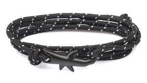 Macro detail of nautical shark-shaped metal clasp on black and white braided rope bracelet