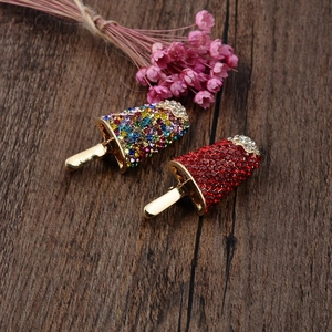 Detailed close-up of crystal ice cream brooches with colorful rhinestones on wood