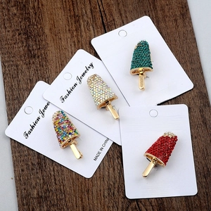 Detail of four colorful popsicle-shaped brooches with sparkling rhinestones on cards