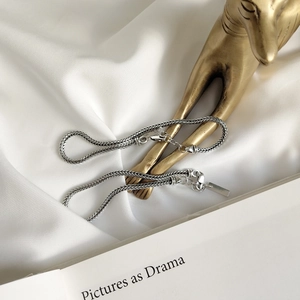 Close-up of S925 sterling silver woven chain with lobster clasp on white silk fabric